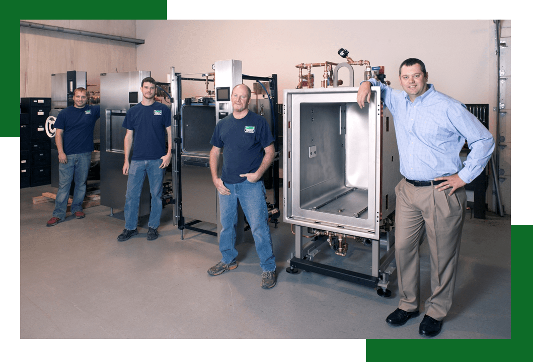 Four employees pose in a workshop showcasing industrial equipment, highlighting teamwork and product development in a manufacturing setting.